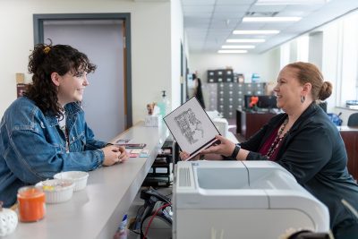 Registrar Sheilah Sites giving a student a diploma