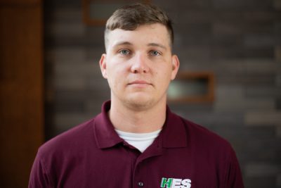 A photo of Colton Plumley in front of a gray brick wall