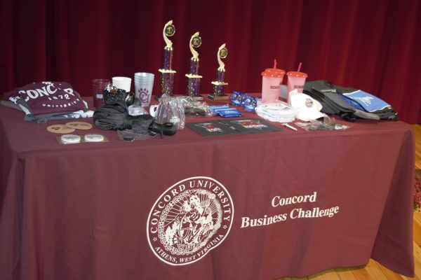A table with Concord University merchandise and Concord Business Challenge trophies sitting on top of it