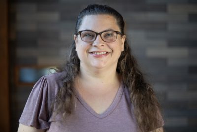 A photo of Elissa Pugh in front of a gray slate wall