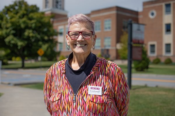 A photo of Joan Pendergast in front of the Concord University Bell Tower