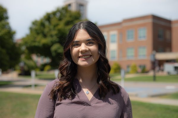 A photo of Madeline Hawkins in front of the Concord University Bell Tower