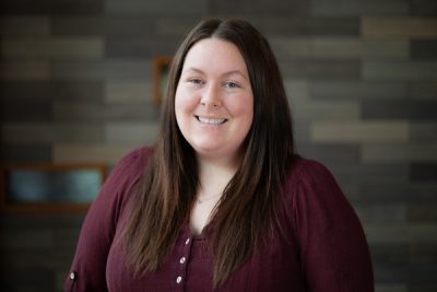 A photo of Megan Thompson in front of a gray brick wall