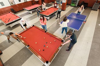 Students playing pool and ping pong in the game room and commuter lounge